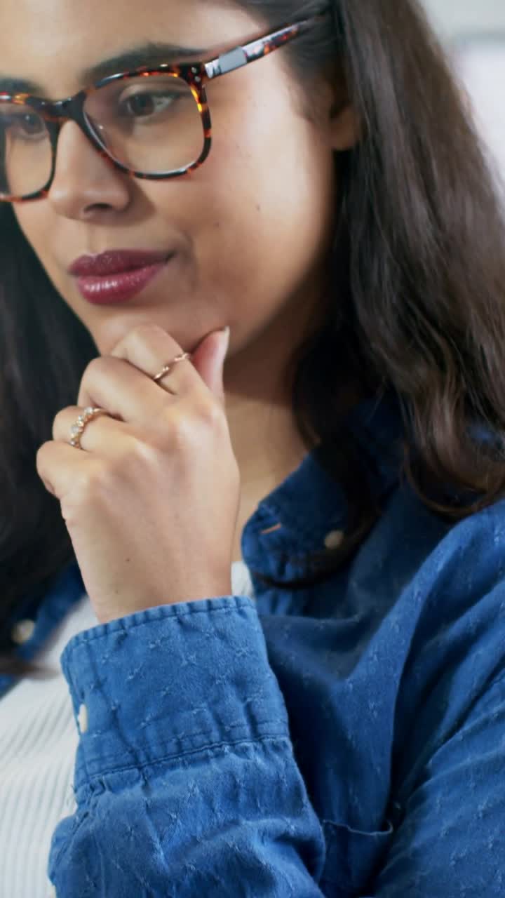 Video verticale: Donna in camicia blu che tocca un tablet bianco, legge e poi riflette a casa, indossando anelli.