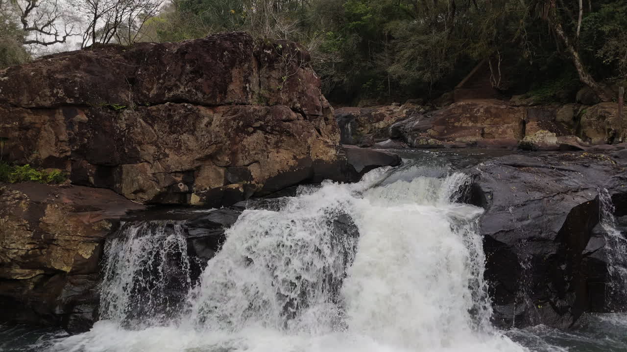 Beautiful waterfalls in the nature, surrounded by stones, drone flight over the water surface, river, dolly shot forward