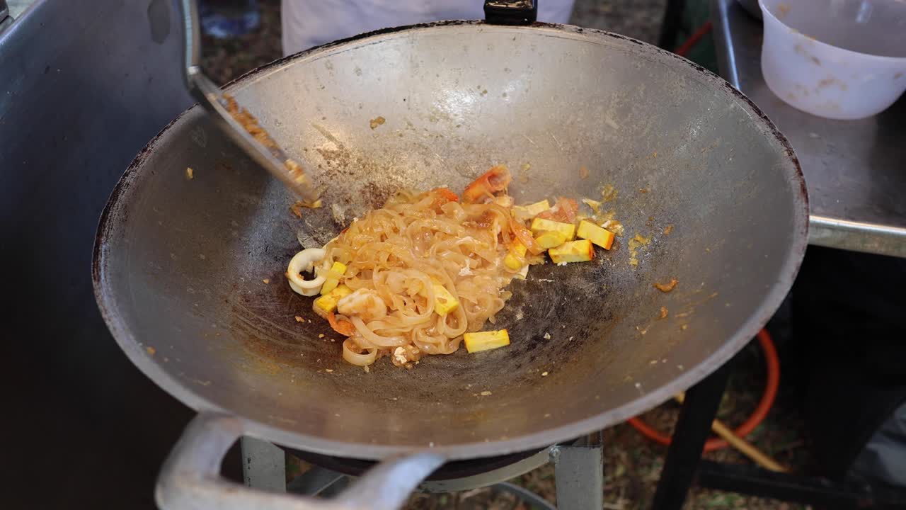 Saltando i noodles Pad Thai in un wok caldo