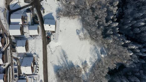 Top-down-aerial-of-wooden-chalets-in-a-Swiss-suburban-town-in-winter