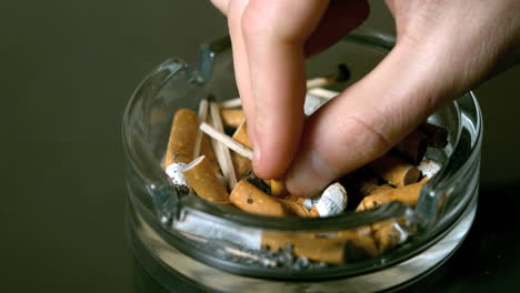 hand putting cigarette out in ashtray