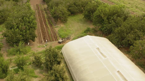 Aerial-of-an-ATV-jeep-arriving-on-a-small-organic-farm-patch-in-the-middle-of-a-green-area