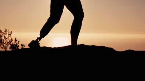 silhouette of a person standing on a clifftop at sunset