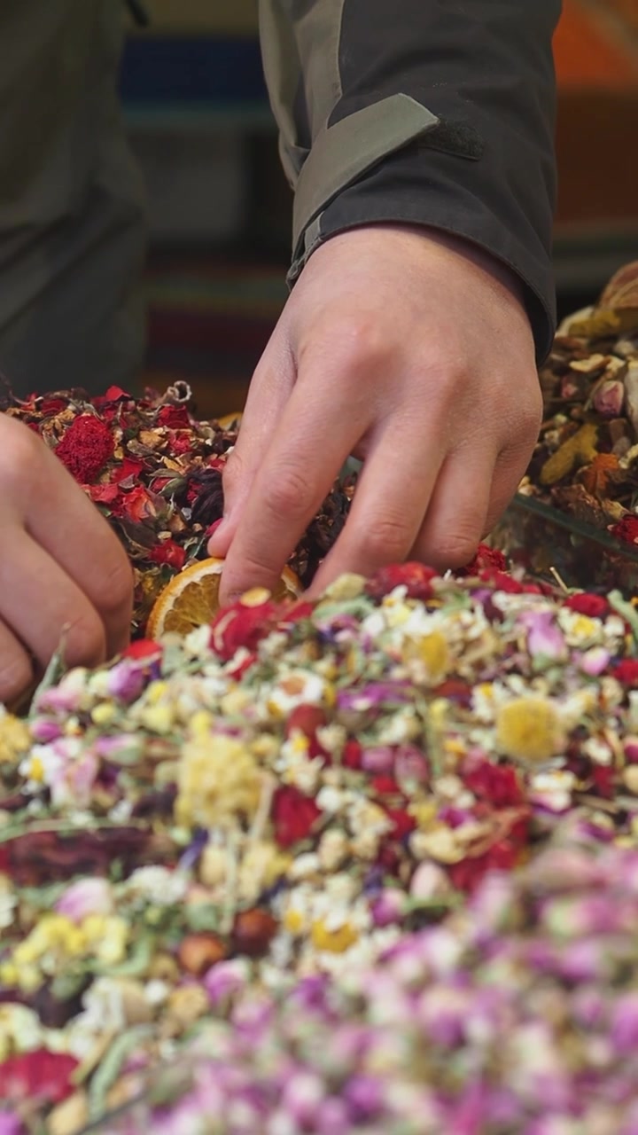 Close-up of Hands Arranging Colorful Dried Flowers and Herbs
