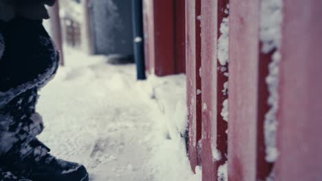 man's legs in pants and winter shoes shaking off snow before entering the house