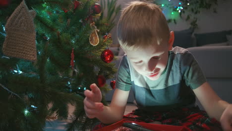 happy smiling little boy opens his christmas gift from santa claus. boy opening christmas gift at home. high quality 4k footage