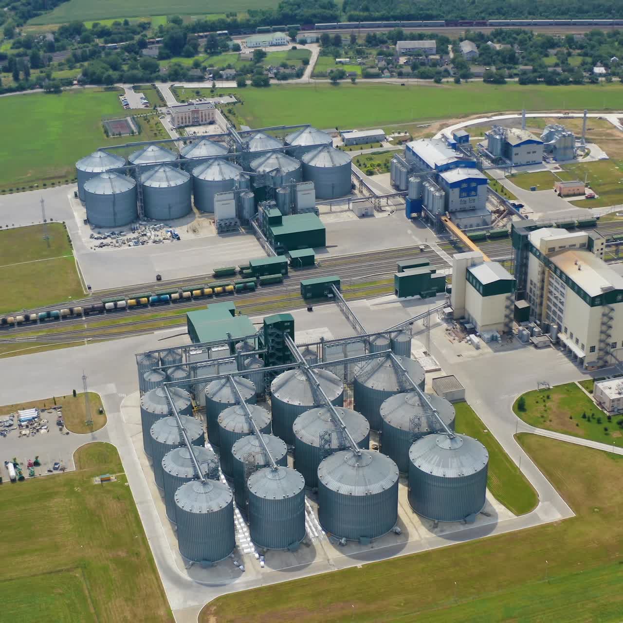 Modern factory with elevators. Industrial area for agribusiness on field in summer. Metal containers for storing grains. Aerial view