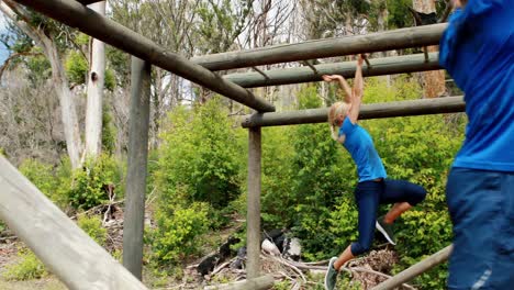 hombre y mujer en forma escalando barras de mono durante una carrera de obstáculos