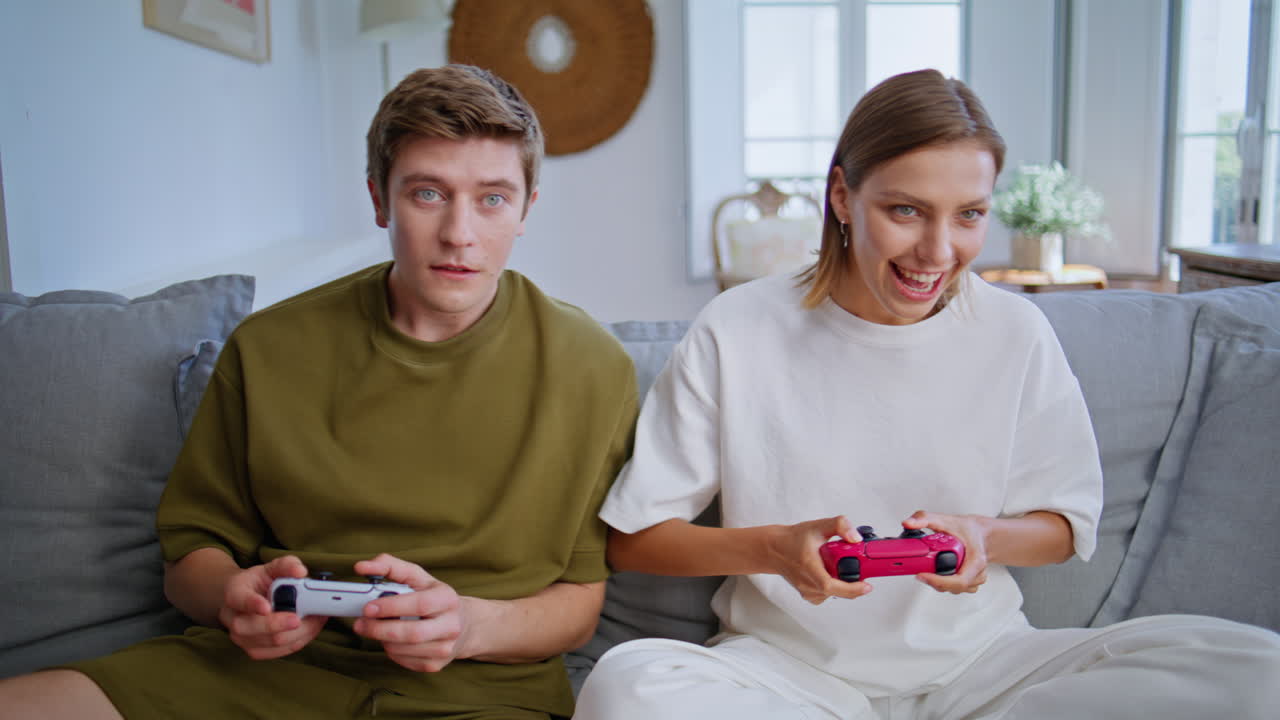 Smiling players enjoy video games sitting couch closeup. Couple playing online