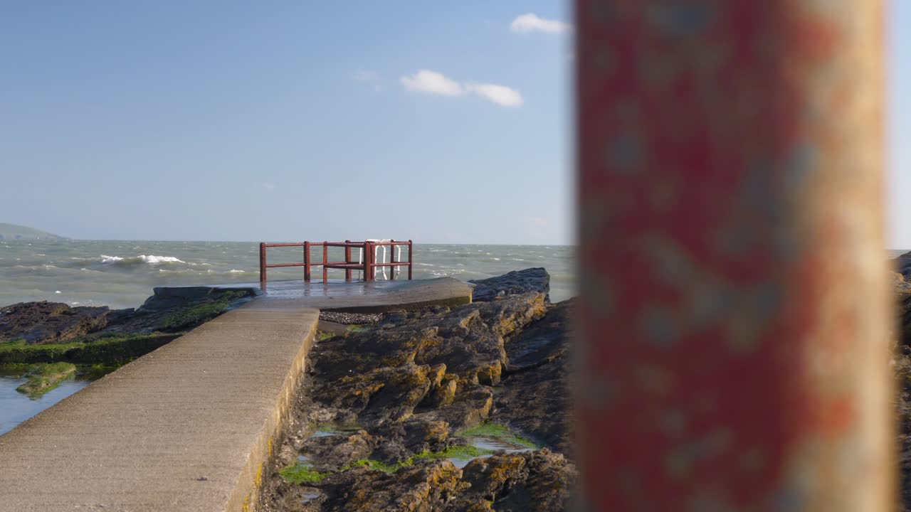 Concrete pier on rocky coastline at Portmarnock beach, Dublin, Ireland with waves crashing in winter