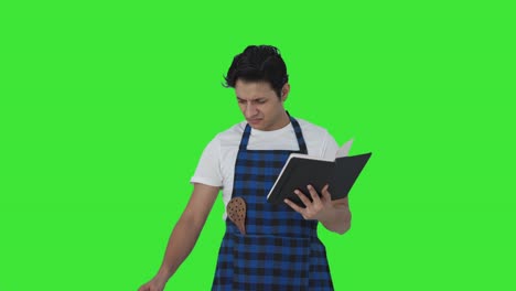 cocinero indio confundido haciendo comida de libro de recetas pantalla verde