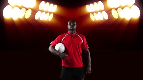 professional rugby player holding a ball in front of stadium spotlights