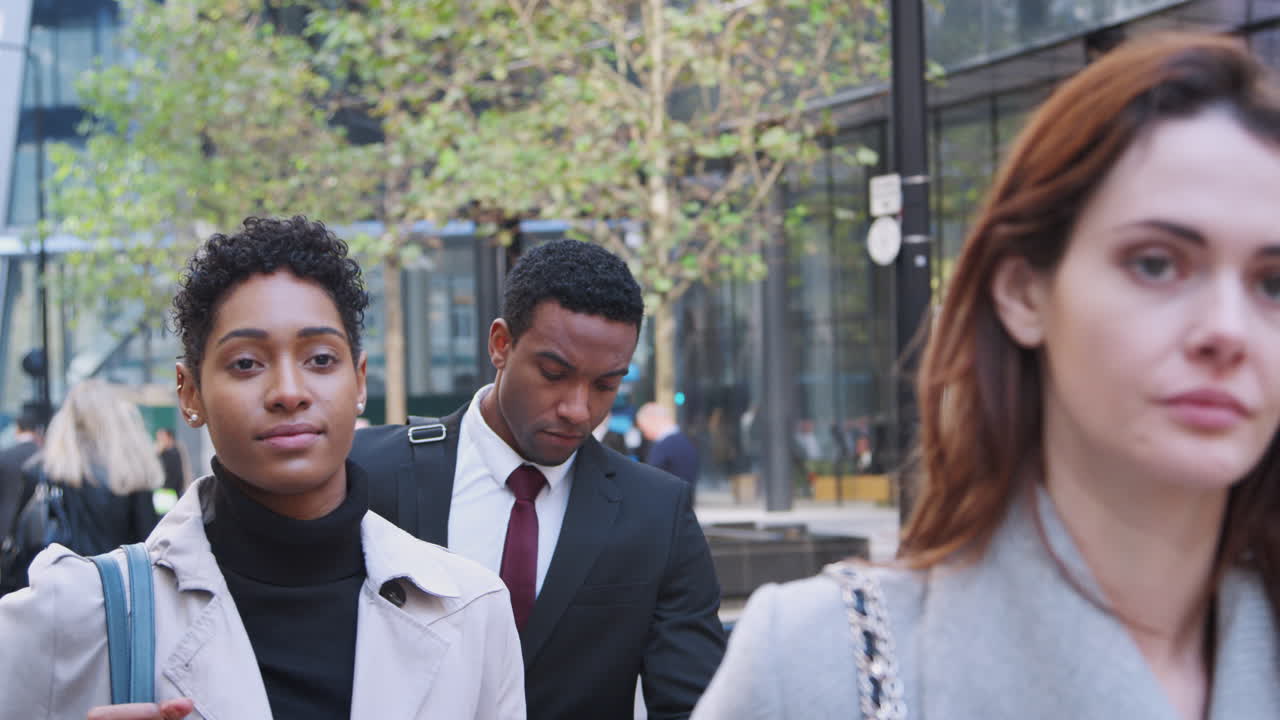 Three millennial business people walking in the city of London, close up, selective focus