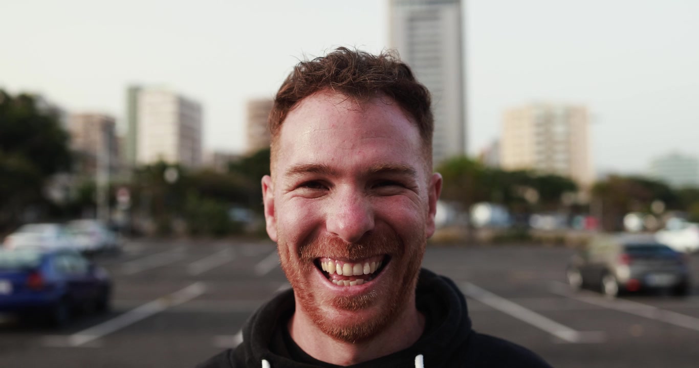 Hombre pelirrojo feliz sonriendo a la cámara en un entorno urbano