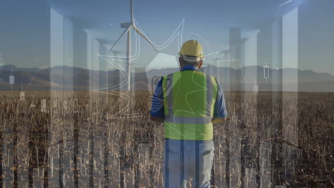 field engineer wearing hard hat and safety vest surveying wind turbines, showcasing finance charts