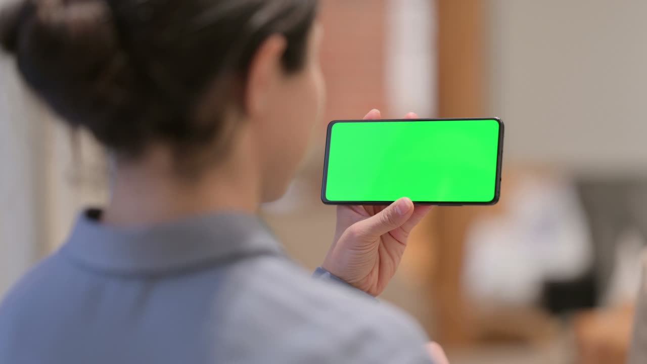 크로마 스크린 을 가진 스마트폰 을 사용하는 젊은 인도인 여성 의 뒷면