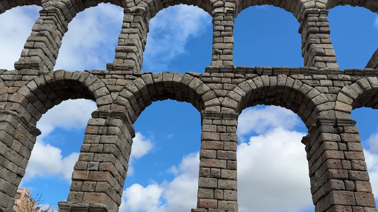 Roman Aqueduct of Segovia with towering stone arches under blue sky.