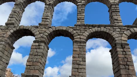 roman aqueduct of segovia with towering stone arches under blue sky.