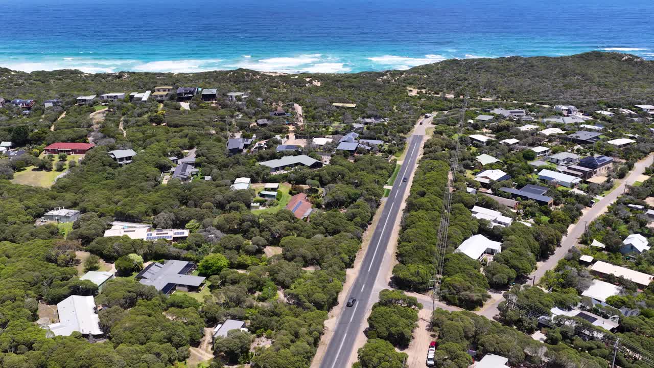 Ripresa aerea dall'alto di una città costiera con case vacanza vicino all'oceano blu
