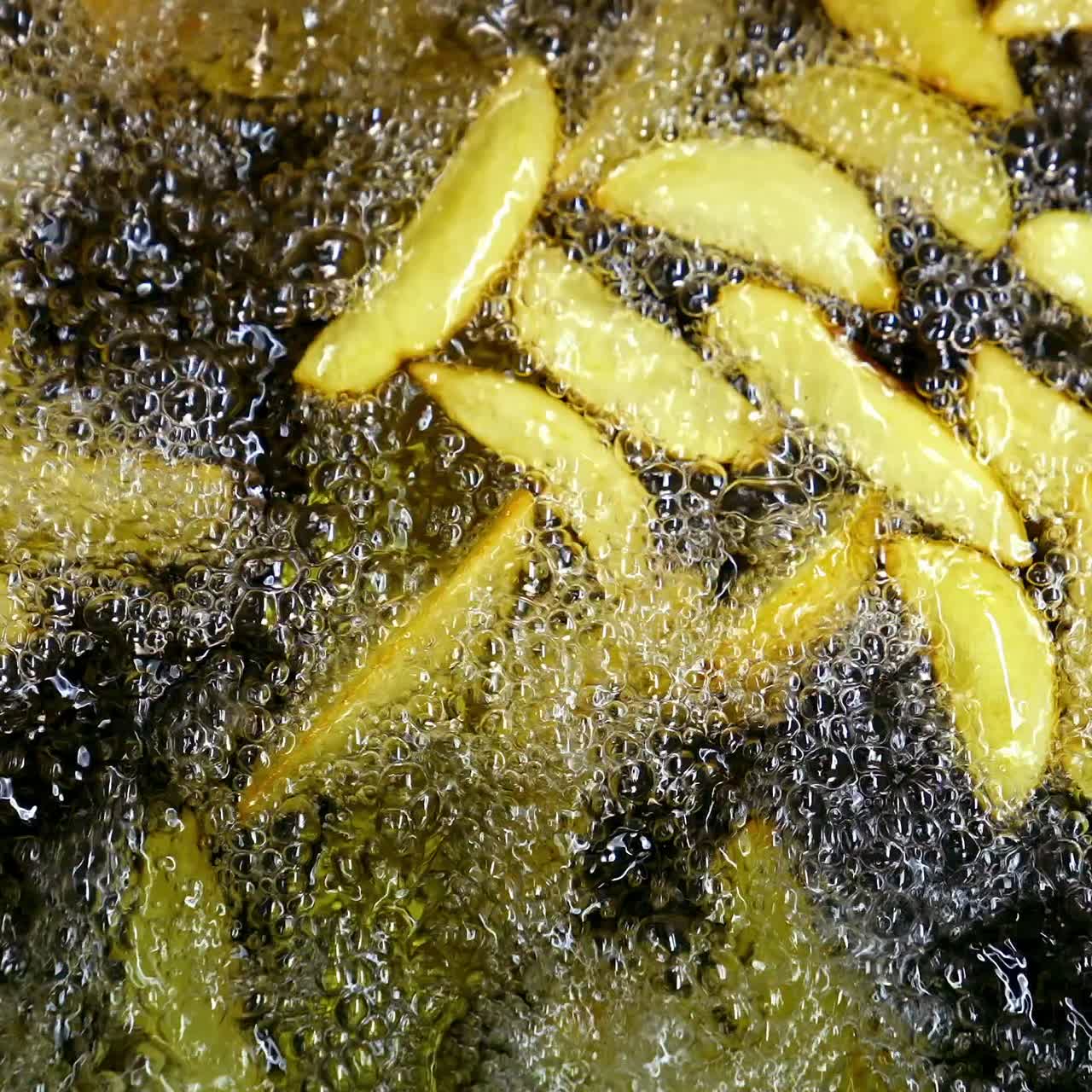 Potatoes are frying in hot boiling oil. French fries fried in restaurant. Video from the top on cooked potatoes