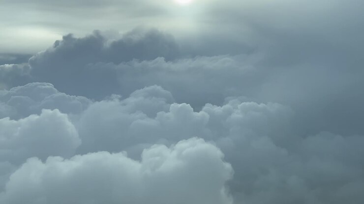 PILOT VIEW, BACKLIT - Descending towards stormy cumulonimbus clouds, commercial flight