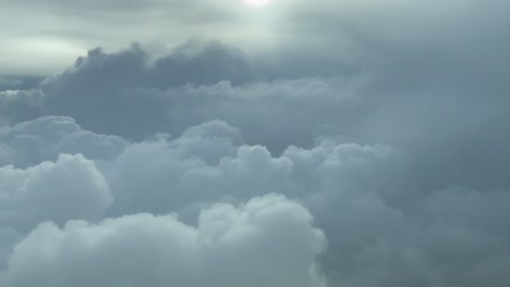 pilot view, backlit - descending towards stormy cumulonimbus clouds, commercial flight