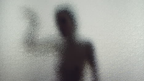 a female silhouette behind the frosted window dances slowly