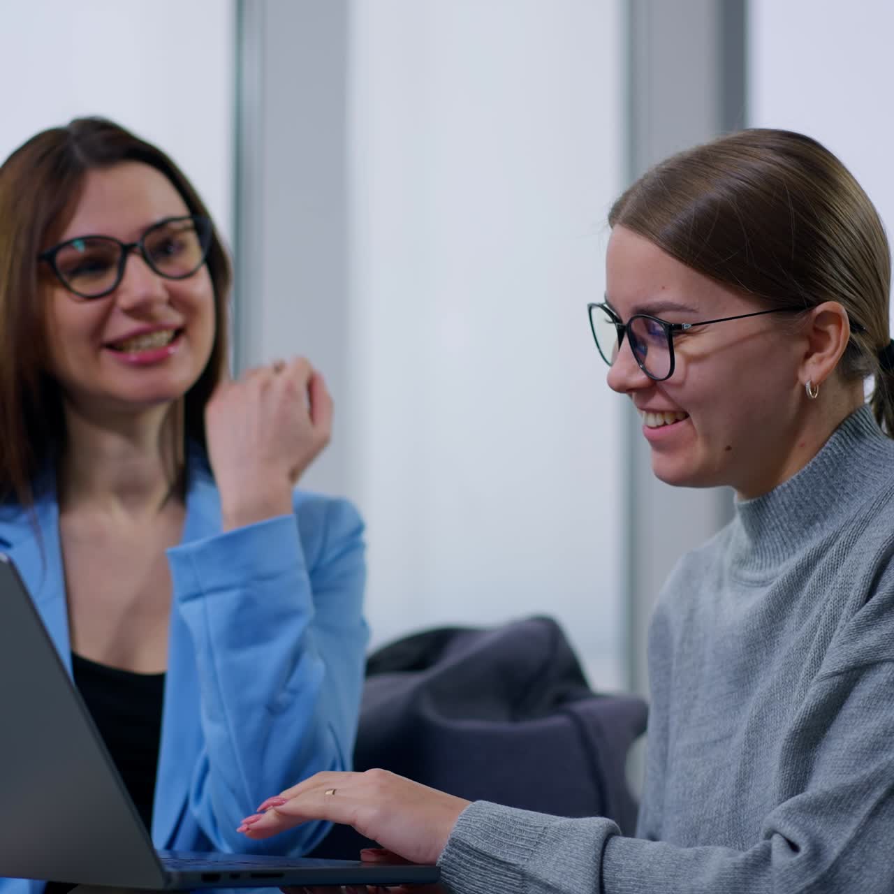 Amigas olhando para um laptop e discutindo fotos ou vídeos alegremente. Mulheres de bom humor se divertindo juntas. Plano de fundo desfocado