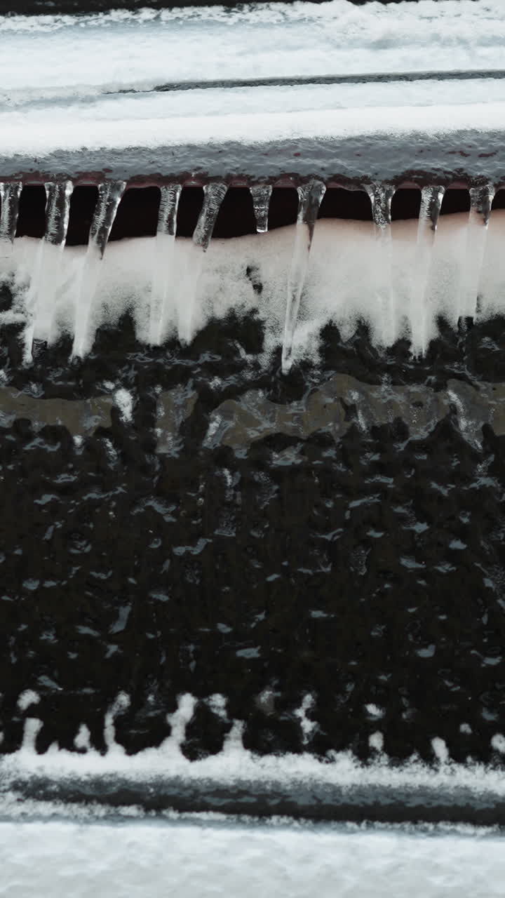 Close-up of a car covered with snow and icicles in winter, showcasing the heavy snowfall and frost patterns on the vehicle and the window
