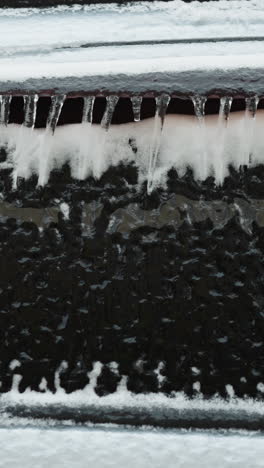 close-up of a car covered with snow and icicles in winter, showcasing the heavy snowfall and frost patterns on the vehicle and the window