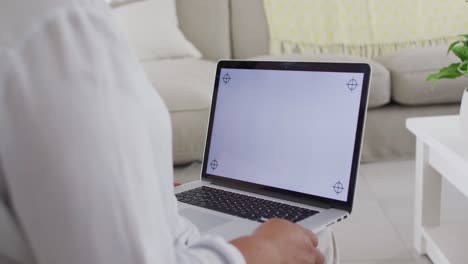 mujer mayor afroamericana sentada en el sofá usando una computadora portátil, con espacio de copia en la pantalla