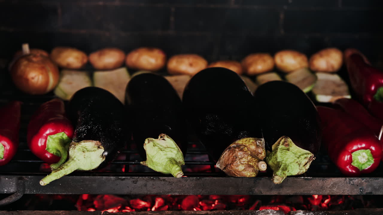 Close up of eggplants, potatoes, onions, peppers and courgettes cooking on a grill