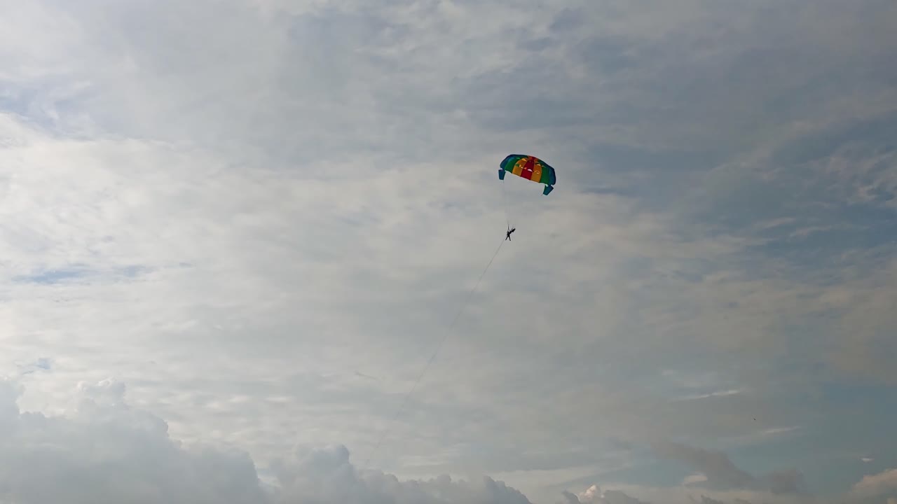Человек занимается парасейлингом в небе с облаками. День, небольшая панорамная съемка, 4K