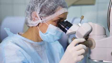 surgeon looking into the microscope at the eye of a patient at the operating room. doctor using microscope during eye surgery process, treatment of cataract and diopter correction.