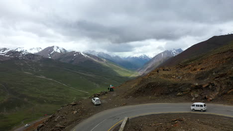 revealing aerial shot starting on a tuk tuk parked on babusar pass in pakistan in the kaghan valley, wide shot