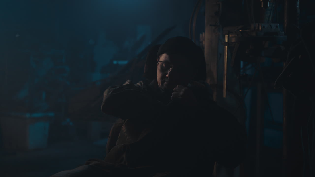 Mysterious man in the workshop at night smokes a cigarette