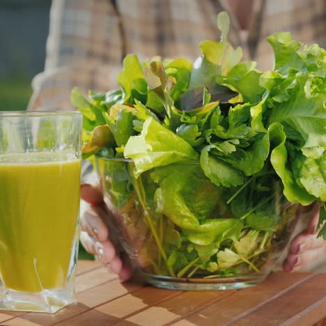 a woman puts a plate of lettuce leaves around a glass of green smoothie