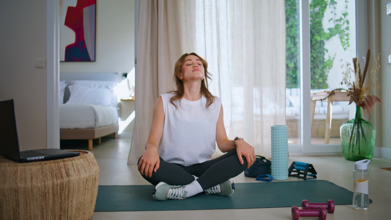 Calm lady preparing workout browsing laptop tutorial at apartment. Young athlete