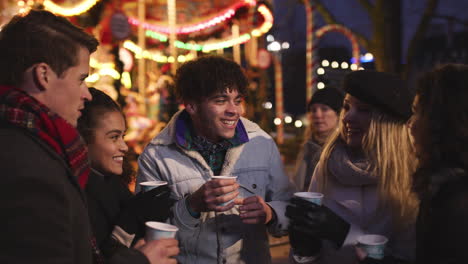 group of friends drinking mulled wine at christmas market