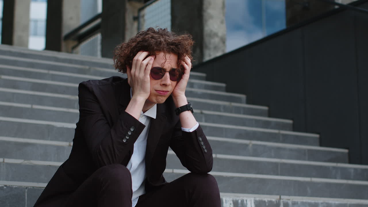 Sad caucasian businessman sitting outside on the steps of an office building bankrupt lost his job