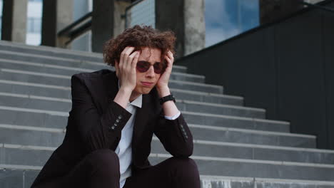 sad caucasian businessman sitting outside on the steps of an office building bankrupt lost his job