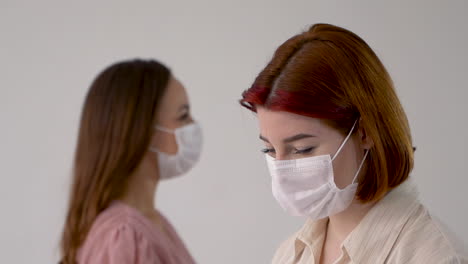 Portrait-of-two-women-wearing-medical-face-mask-and-looking-at-camera.-Close-up.