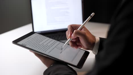 businessman signing a business contract with stylus pen on tablet at night. man signing contract on tablet at office. business and technology concept. electronic signature concept