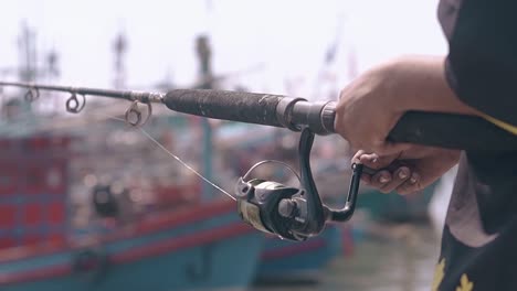 boy hands spin reel on wooden rod and take fishing line