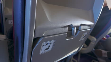 close-up view of the back of an airplane seat featuring safety instructions and a magazine holder