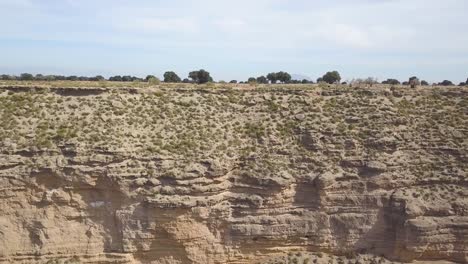 Toma-Aérea-Lateral-De-Un-Barranco-De-Roca-En-Una-Zona-Desértica