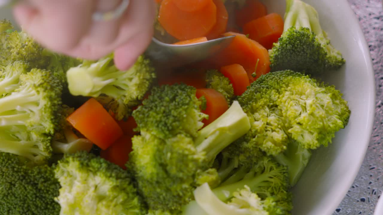 Rotating Overview of Vegetable Bowl with Peas, Broccoli, Carrots. Female Hand Serving Herself at Dinner Table. Healthy High Fibre Food.