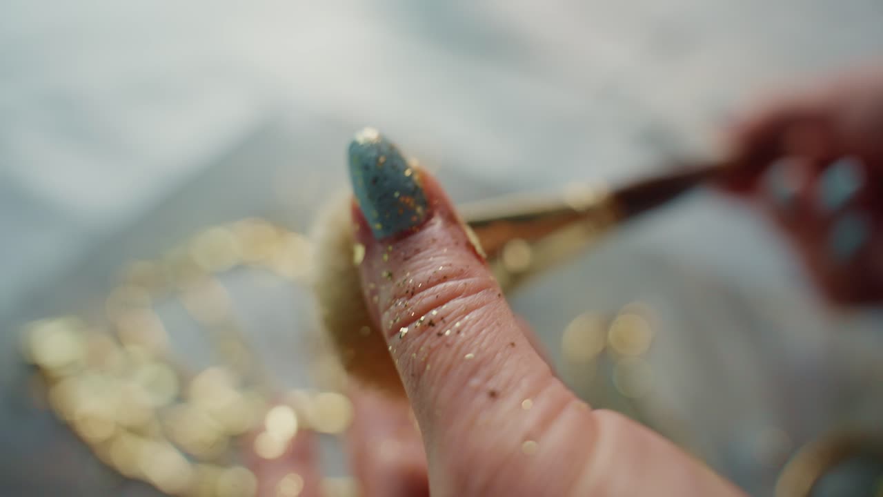 Applying Gold Glitter to Blue Nails