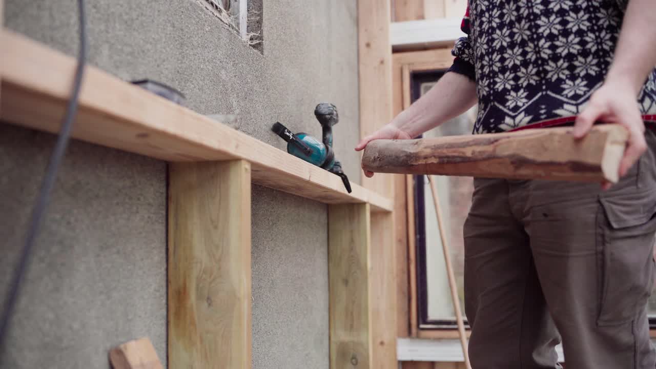Uomo con trapano a batteria che avvita un pezzo di legno su un rinforzo