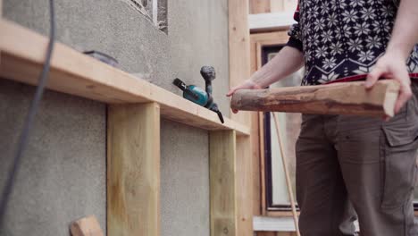 Hombre-Con-Perforador-Inalámbrico-Atornillando-Un-Trozo-De-Madera-En-El-Puntal